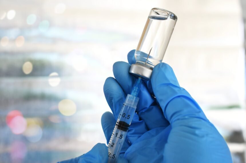 (Não usar depois da publicação. Em caso de dúvidas, falar com Foto) Medical personnel filling a syringe needle with generic vaccine booster from vial